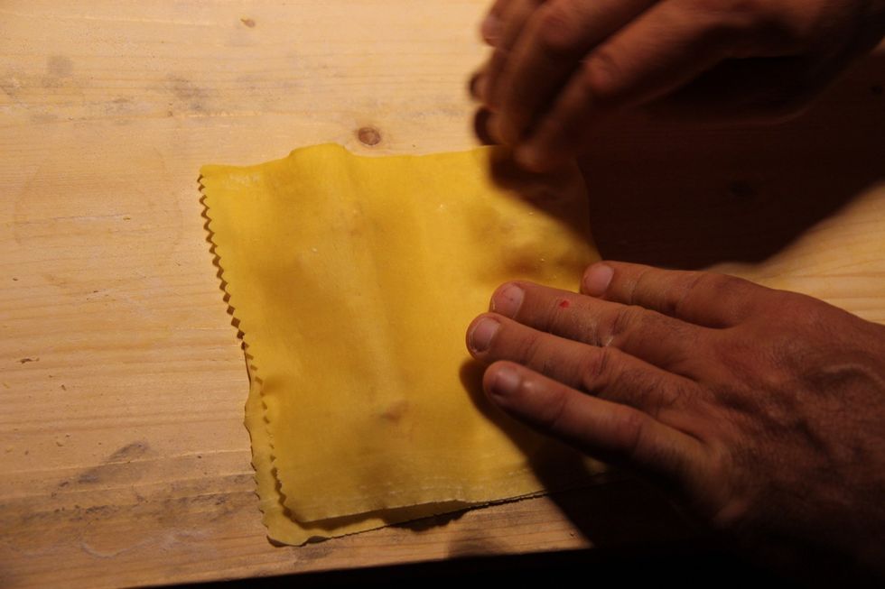 Brush the pasta with egg white to hold the dough together. One brush, one dip between the fillings. Fold the dough over to make edges meet.