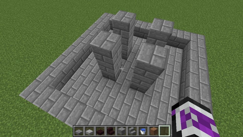 Build 4 towers at the corners of the middle 3x3 area that are 3 blocks high.