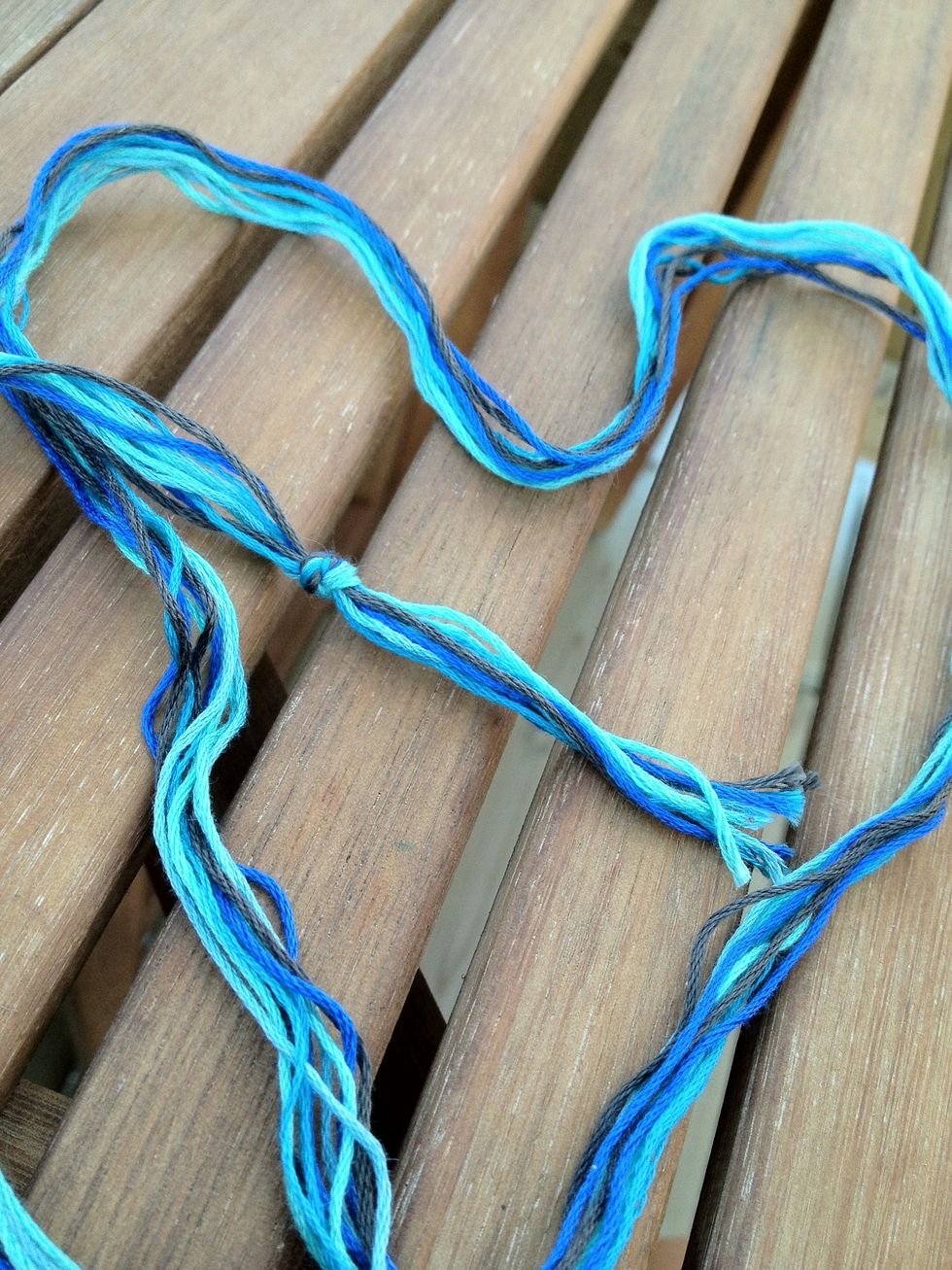 Bunch your strings together and tie a knot at one end. You could also double the length of the strings and fold in half, tying in a loop knot instead. So you would have 3 strings, 1 of each color.