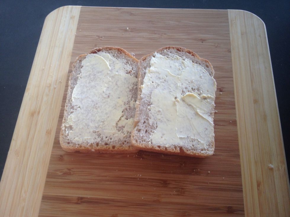 Butter both sides of two slices of bread.