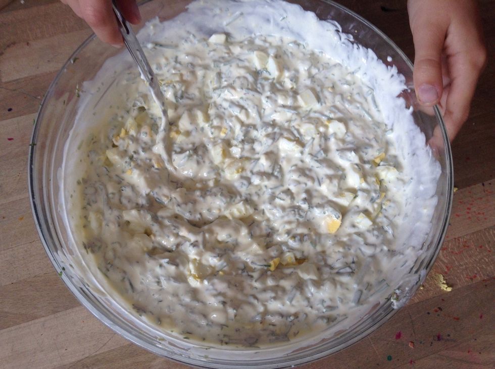 By and by mix your yoghurt and sour cream with the herbs. Add the roughly chopped hard-boiled eggs. Finally season with salt and pepper.