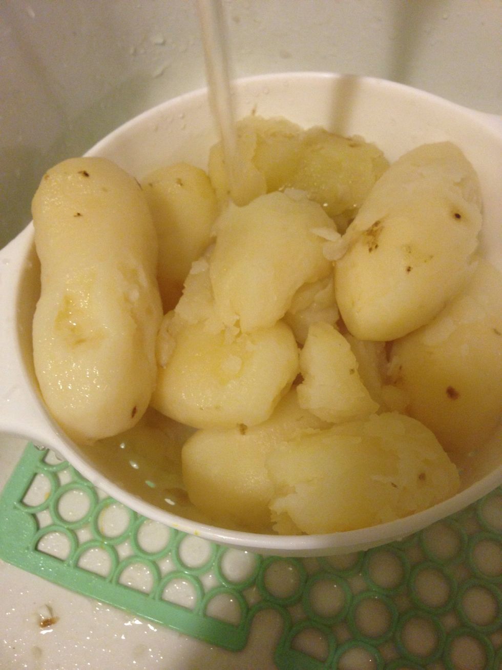 By now the potatoes should be all boiled and done. Pour them into the strainer and drain the water. (BE VERY CAREFUL). Run cold water onto the potatoes to cool them down.