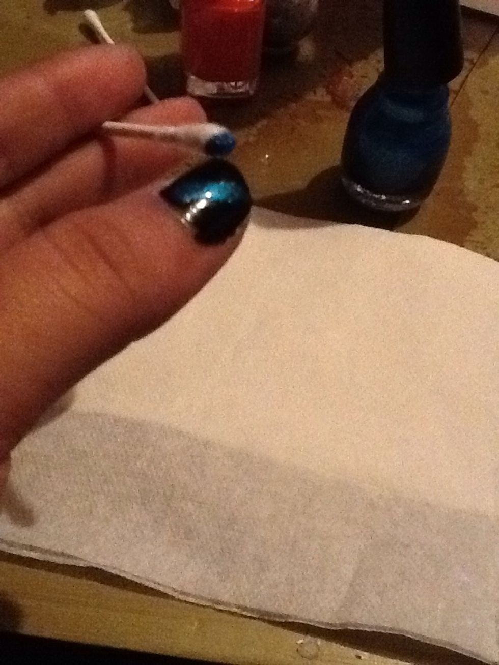By smearing a little blue polish on a q-tip, make a streak on your nail after the black coat is set and dry