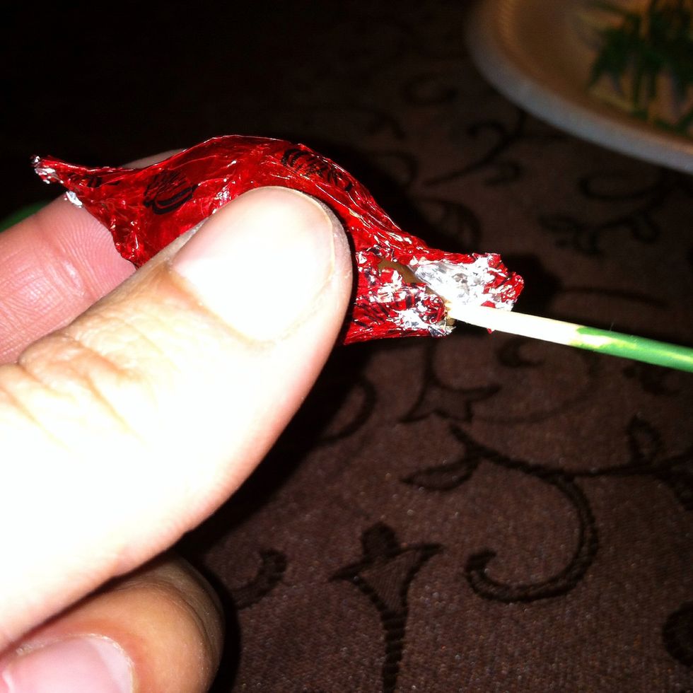 By this time everything should b dry. Now grab a toothpick and a chocolate rose. Put the toothpick inside the chocolate like this. Use the side that is not painted.