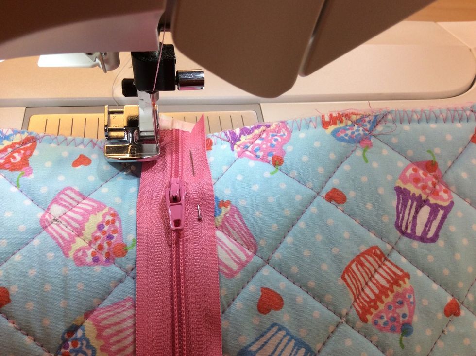 Byt till pressarfot E , en pressarfot till f\u00f6r att sy dragkedjor. Sick-sacka allra l\u00e4ngst ut p\u00e5 dragkedjan.