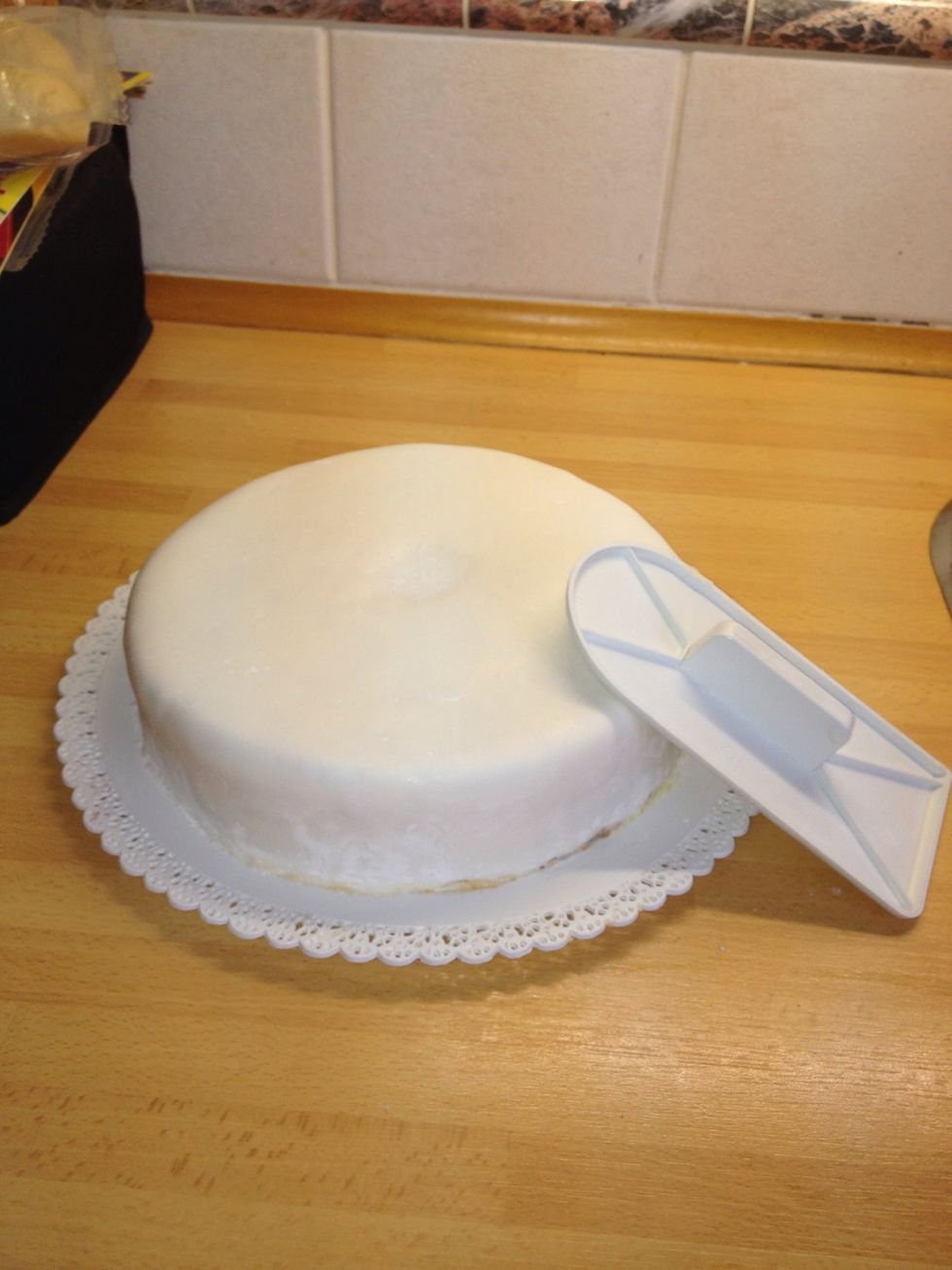 Carefully place the fondant on the cake. Cut off excess fondant. Fit the fondant using any flat item you have.