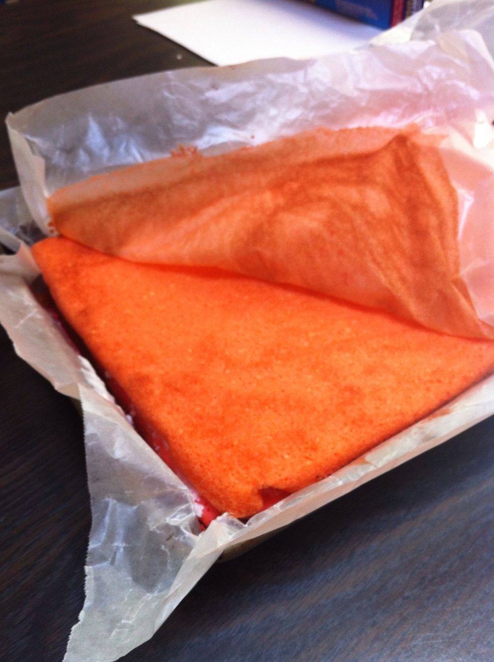 Carefully place the orange layer on top of the red one and peel the parchment paper off.