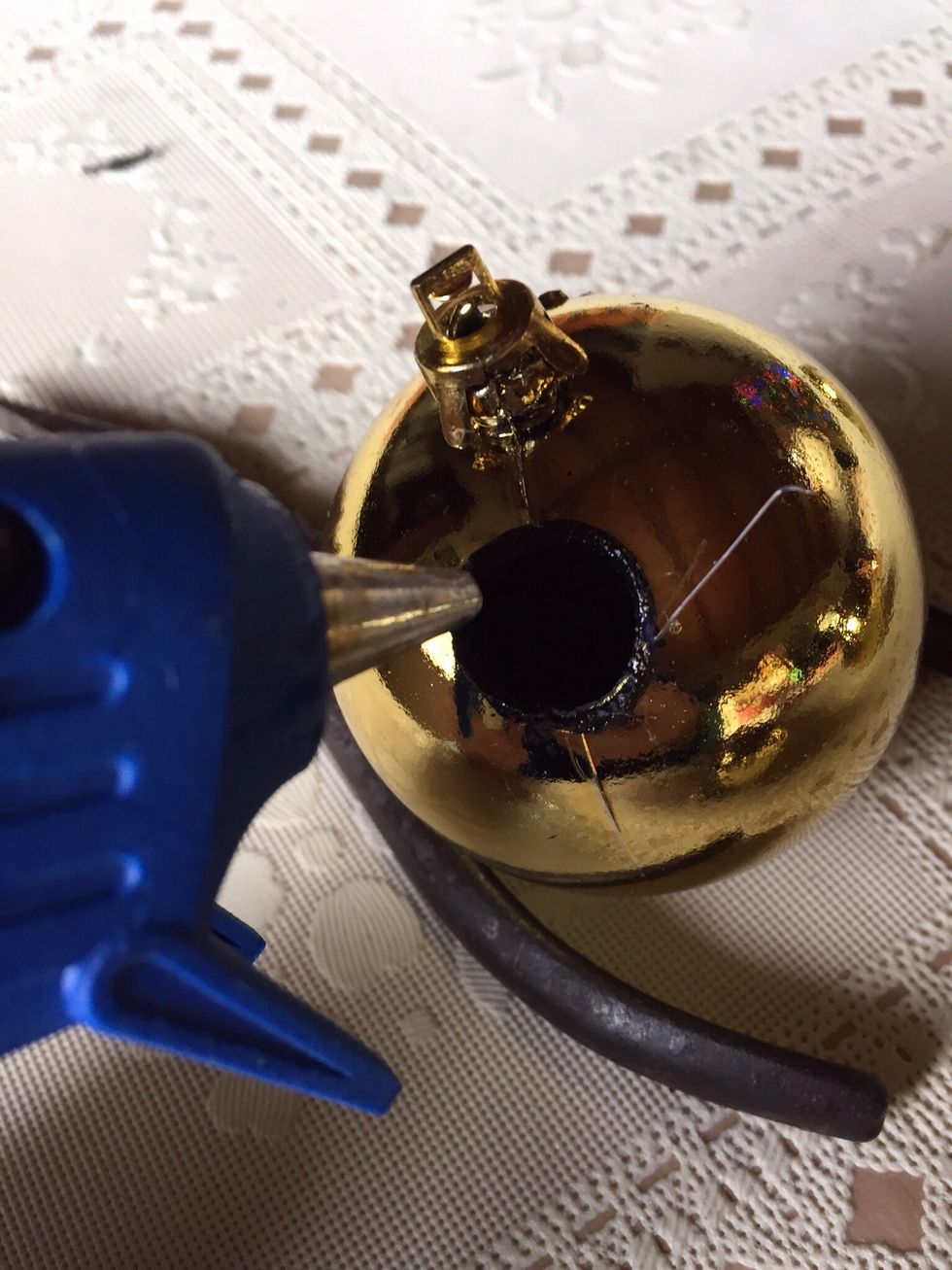 Carefully run a line of hot glue on the inside hole, where you will be inserting the smaller ornament.