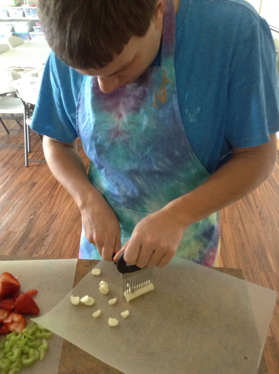 Carefully using cut guiding tool, knife, and cutting board slice the cheese stick into small circles