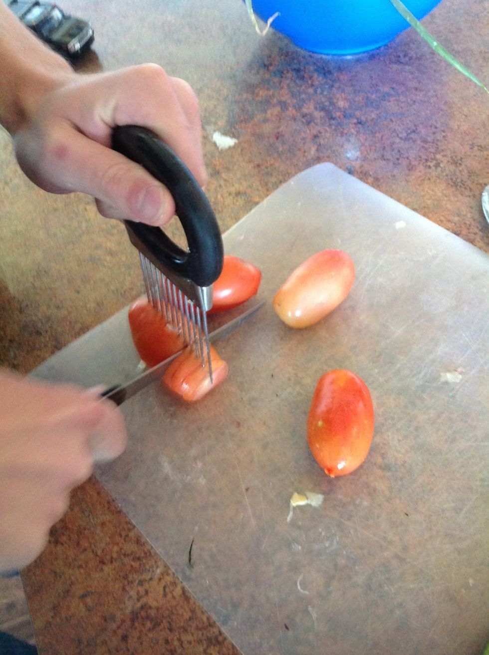 Carefully using cutting board and knife cut the tomato into thin slices.