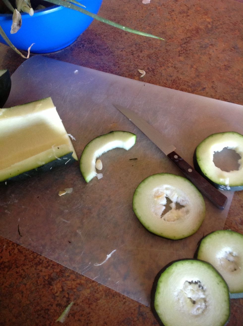 Carefully using cutting board and knife cut the zucchini into thin slices.