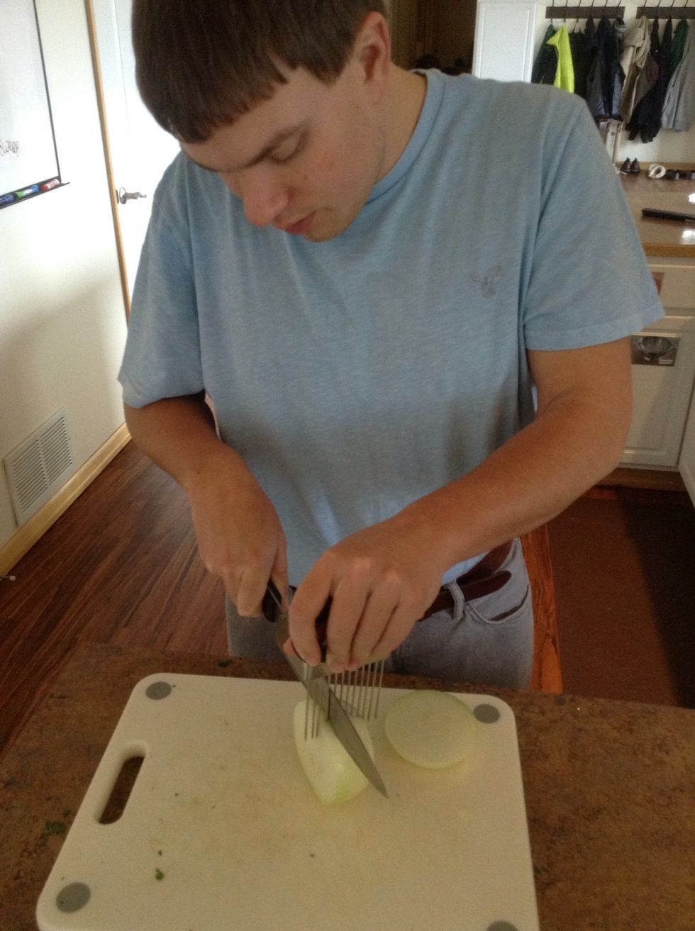 Carefully using cutting board, knife, and cutting guide cut the onion into slices