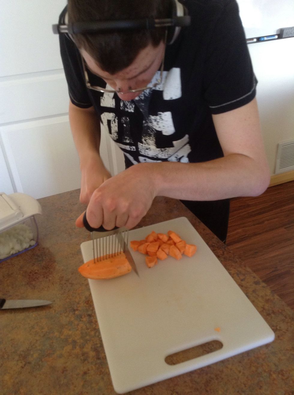 Carefully using cutting board, knife, and cutting guide cut the sweet potato into small cubes