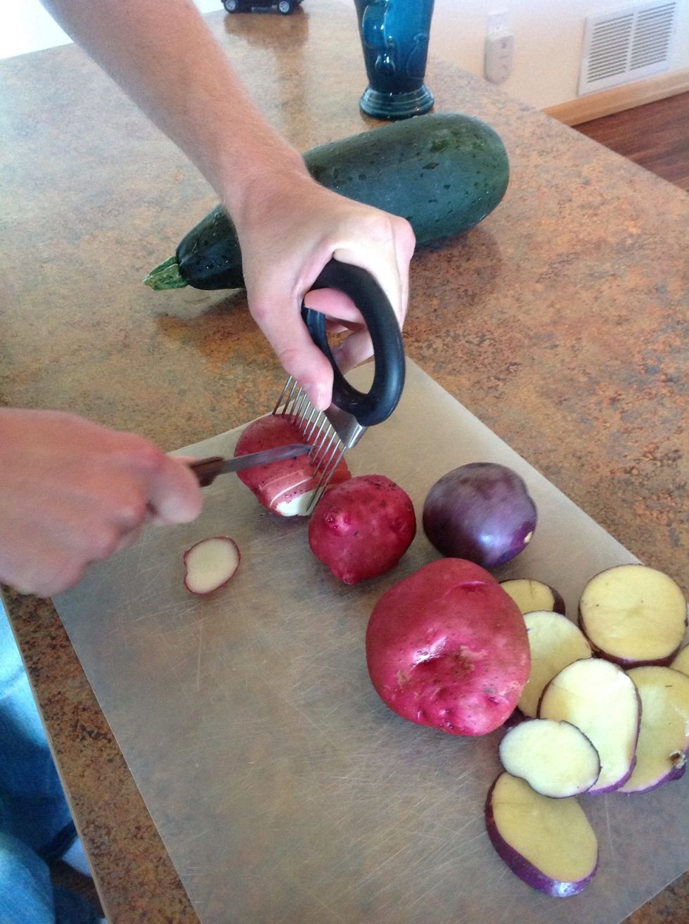Carefully using cutting board,knife, and cutting tool cut the potatoes into thin slices.