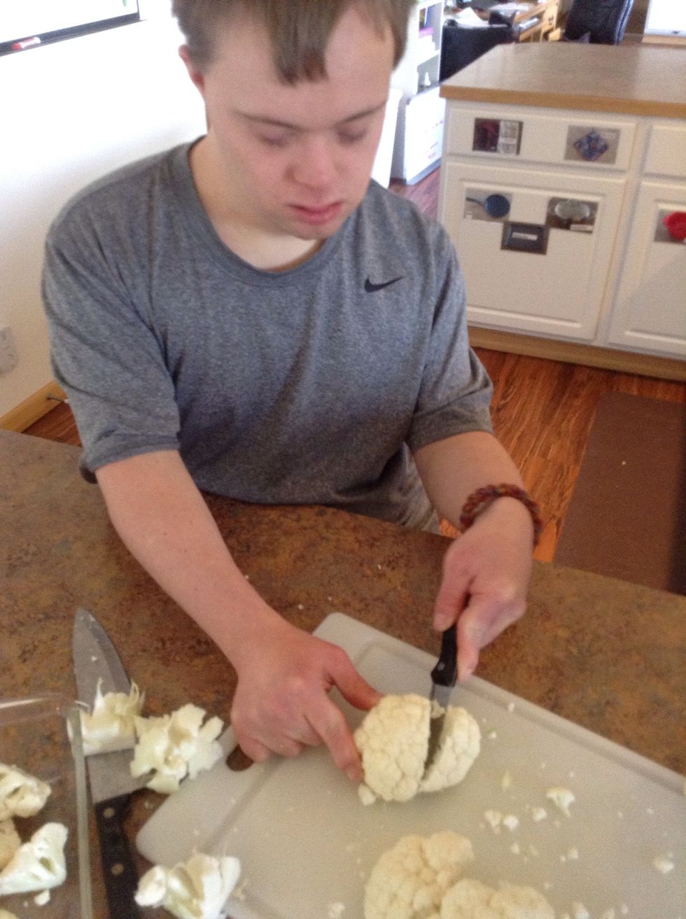 Carefully using knife and cutting board cut the florets off of the cauliflower