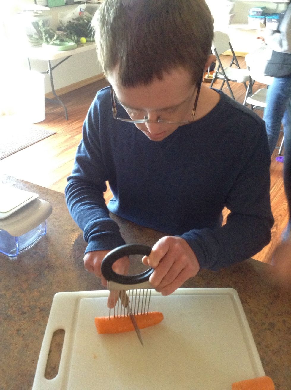 Carefully using knife, cutting board, and cutting tool cut the carrots into 4 pieces.