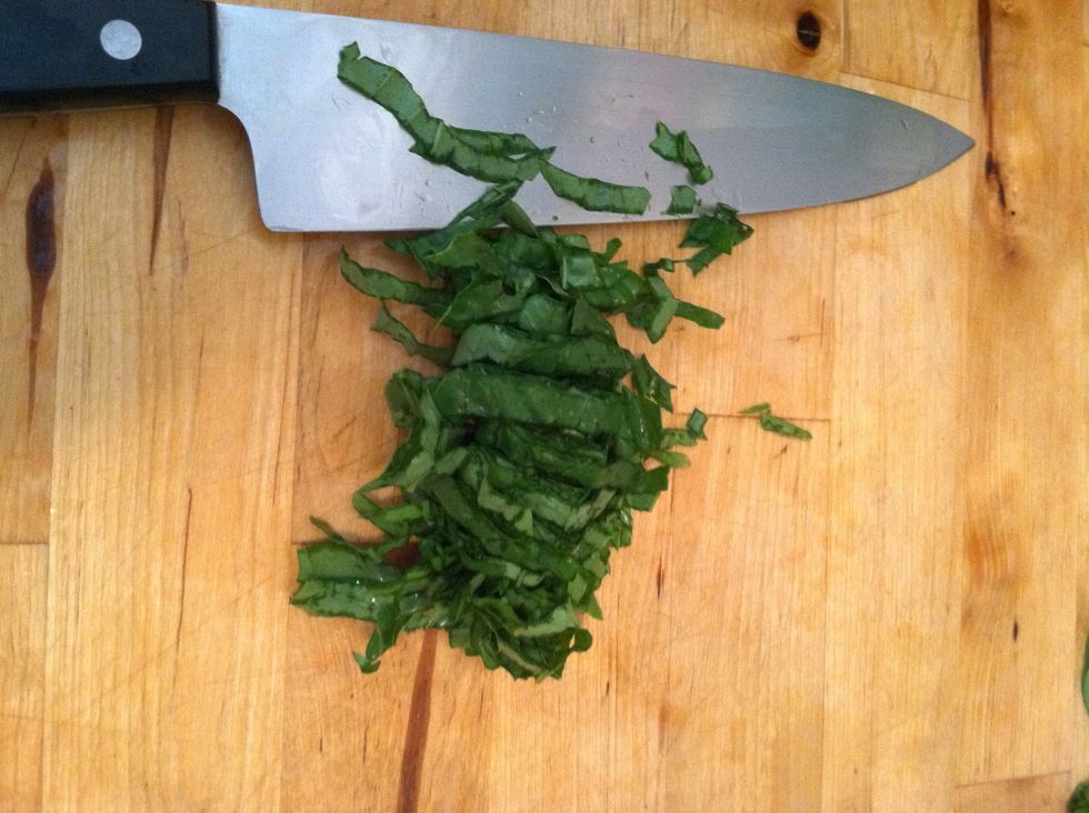 Chiffonade the basil by rolling the basil leaves into a roll and cutting across the leaves to make little shreds. Put these basil shreds into the bowl with the cheese.