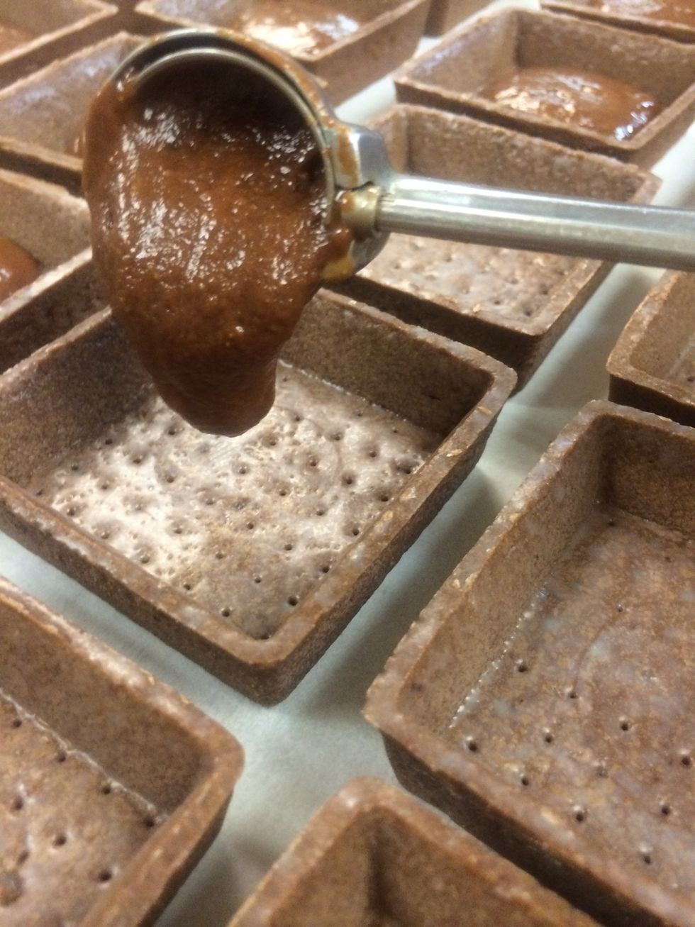 Chocolate tart shells are filled with a heavy tablespoon of the milk chocolate peanut butter ganache.