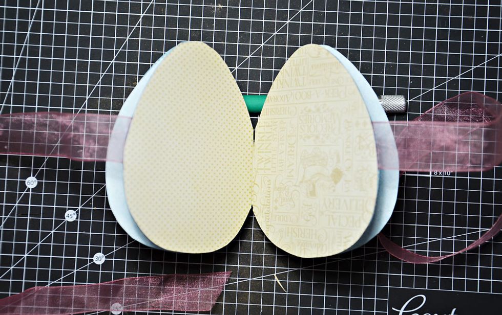 Choose some ribbon to tie your egg closed. Attach the ribbon  to the back side of the inside card backing. Now attach the inside card to the egg halves as shown.