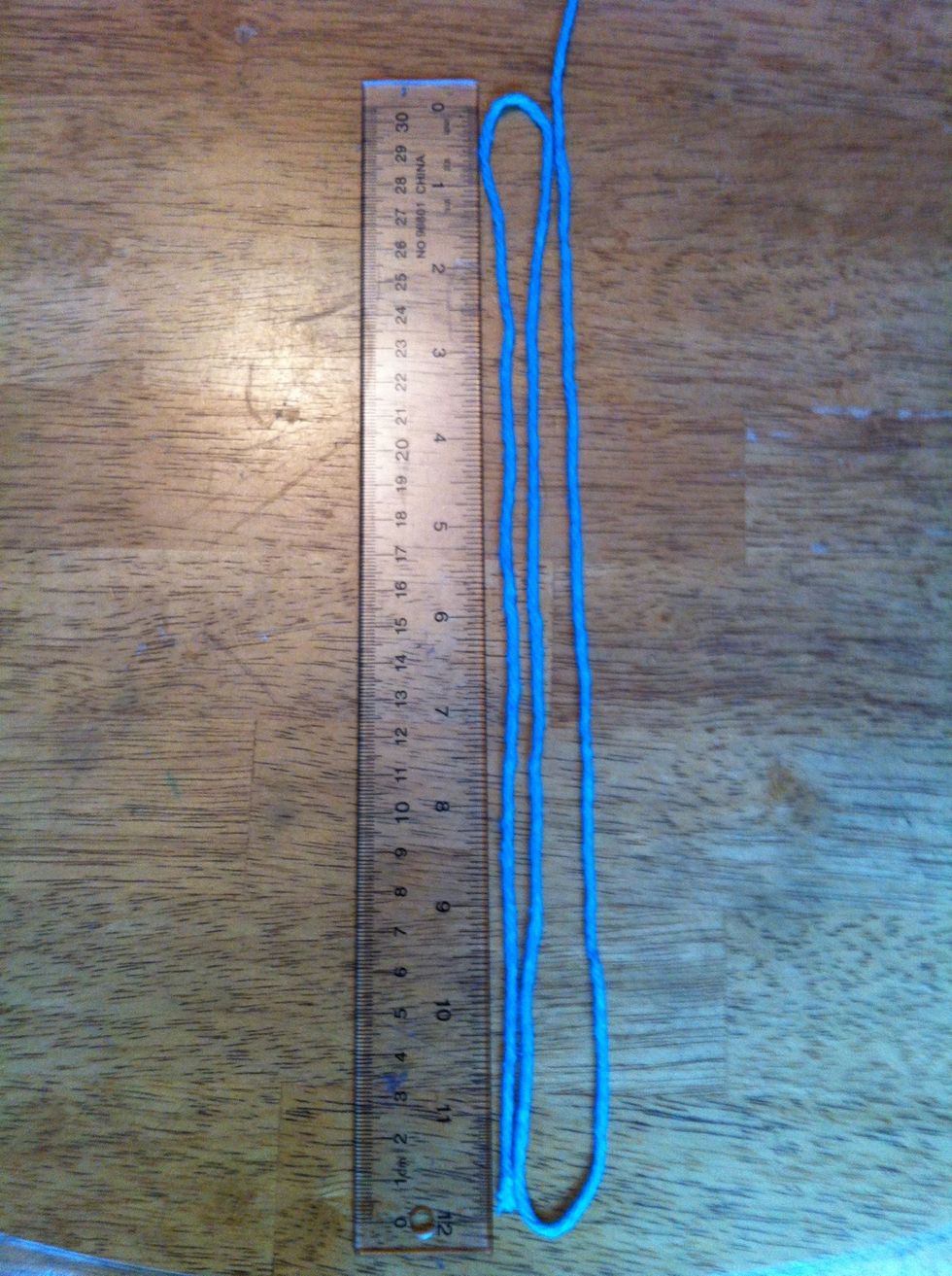 Choose which colour is going to be on the outside. In my bracelet, the blue is going on the outside so I am measuring it at 3 feet (Two loops on a 1 foot ruler.) This is the base yarn.