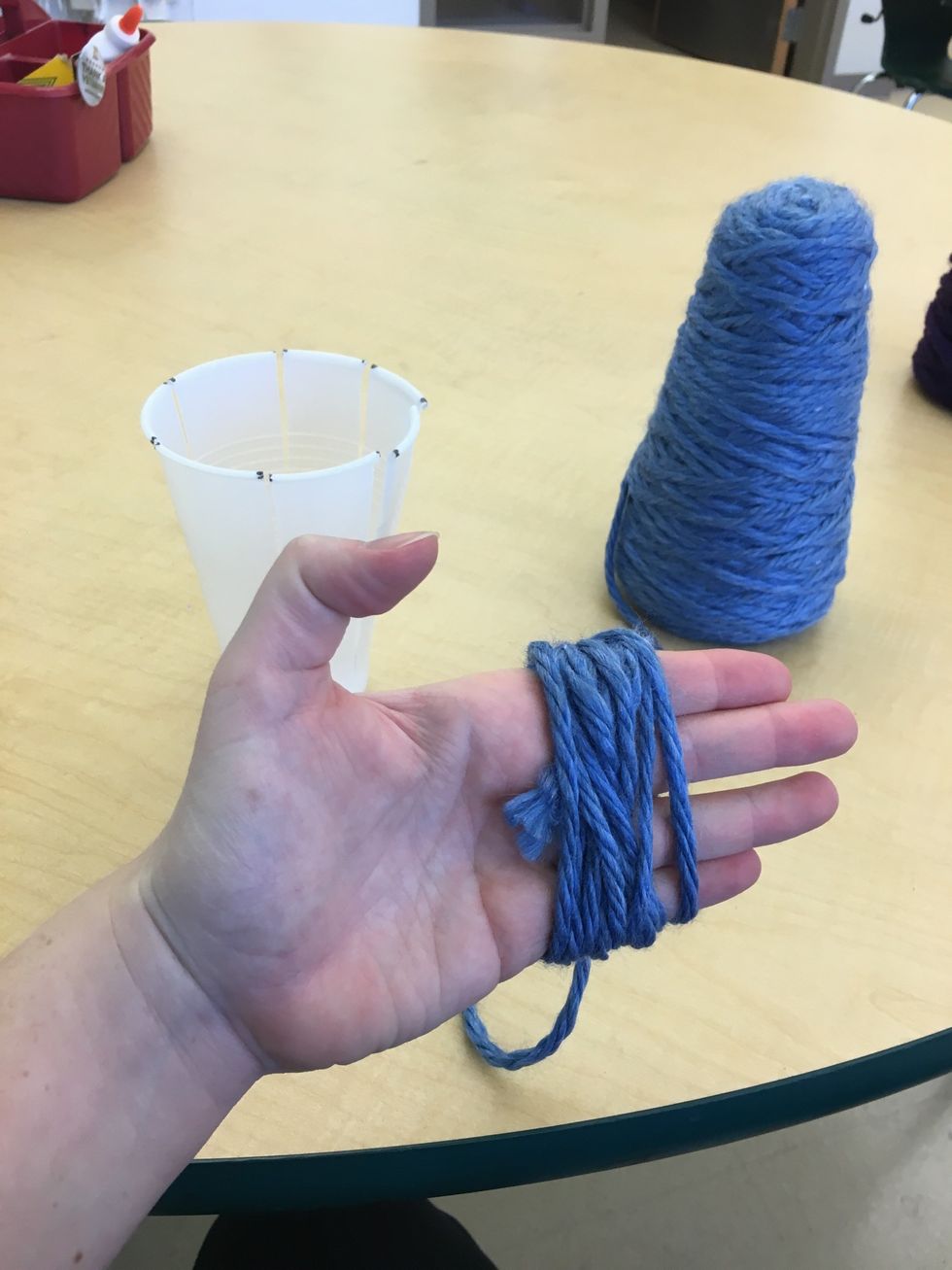 Choose your first color or yarn. Wrap the yarn around your hand 10 times for the first layer to be woven. Cut the end of the yarn from the skein using your scissors.