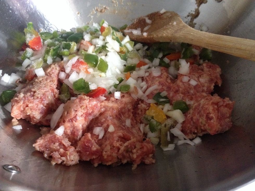 Chop the green pepper, then brown the sausage with the chopped onion and chopped peppers. Drain excess oil.