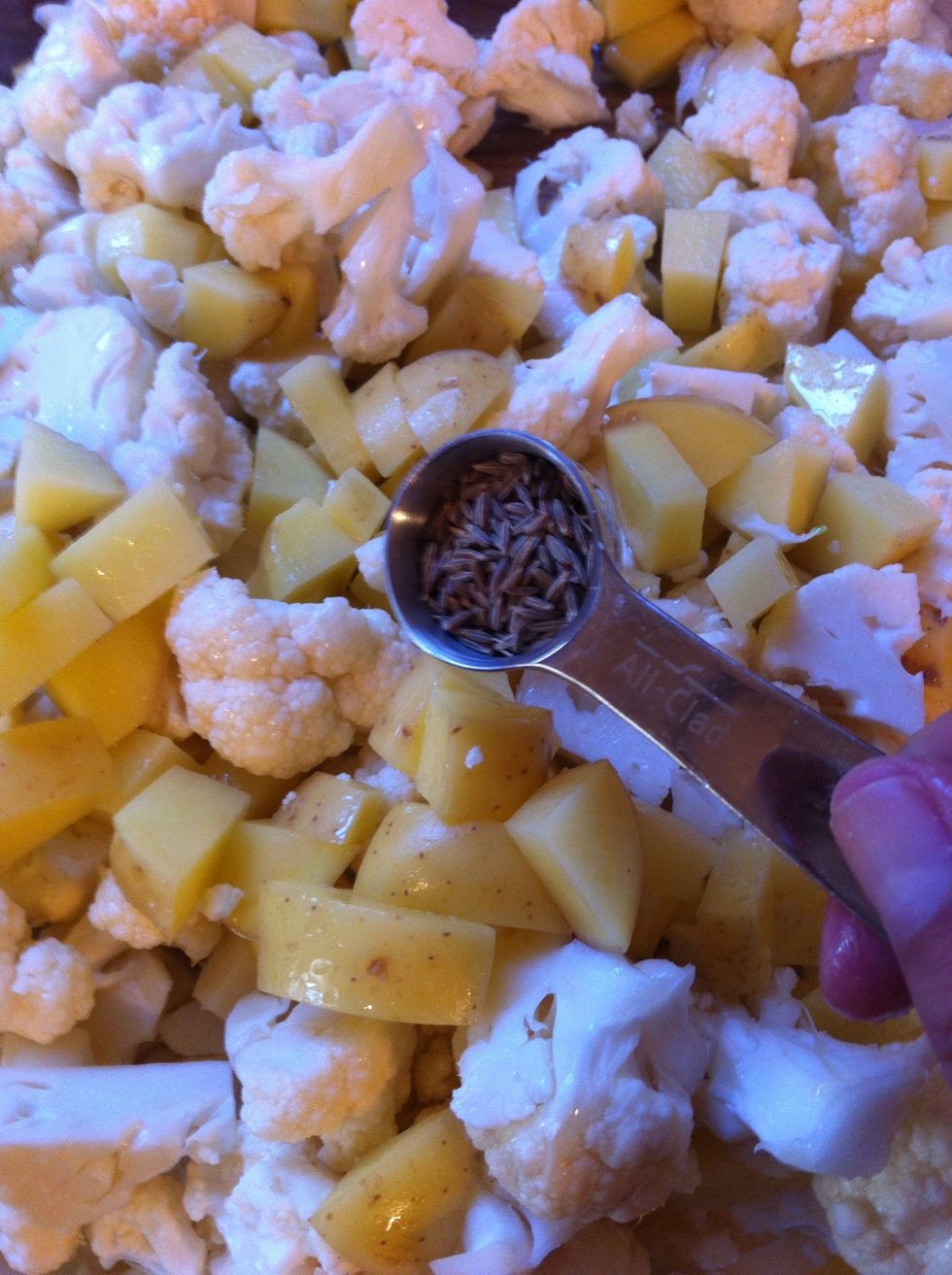 chop you potatoes (peeled or not) into 1/2 inch cubes and the cauliflower into 3/4 inch florets. and mix them together with 3T. of oil, cumin seeds, and 1/4 t. salt.