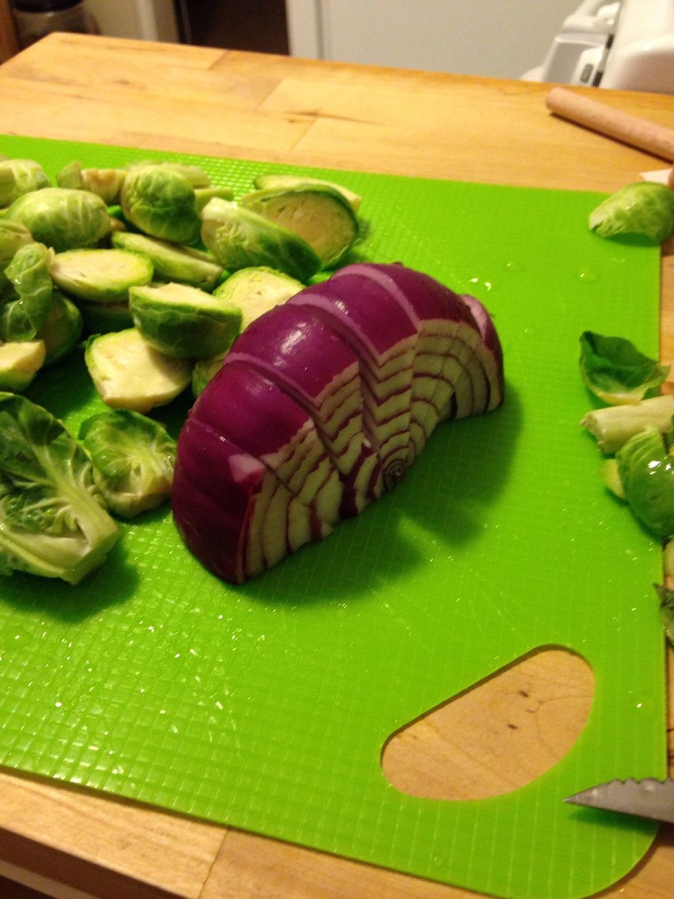 Chop your Brussels sprouts in half and cut an onion into slices.
