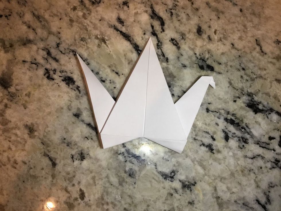 Chose a side to fold down a small part in the very center of the triangle to create a head