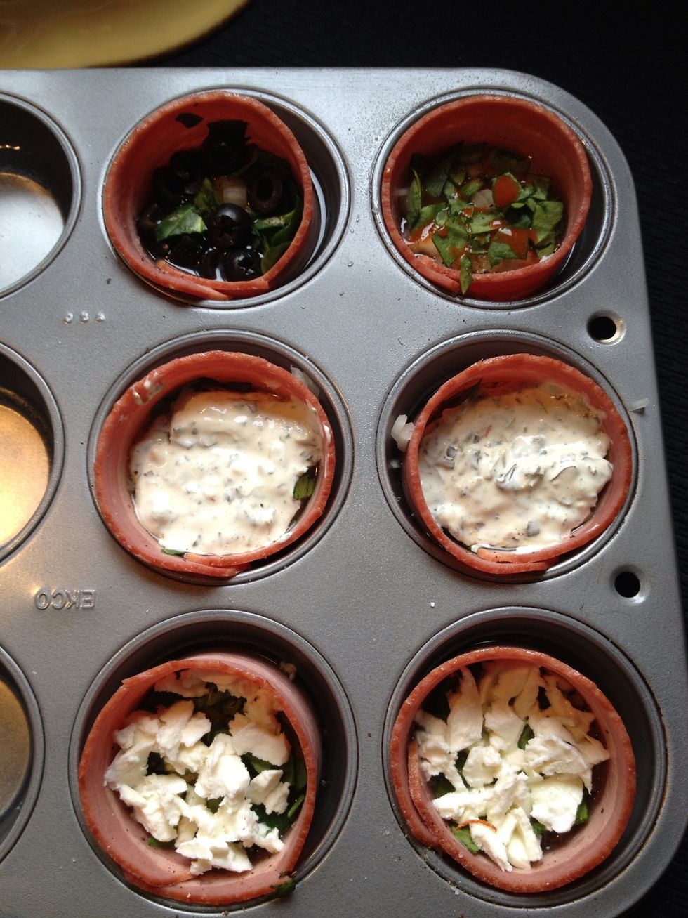 Circle 1 strip bacon per muffin tin, add 1 egg per cup and add onions, spinach, salt, pepper and garlic powder to all 6. I did two with cheese, two with dip, one with hot sauce and one with olives.