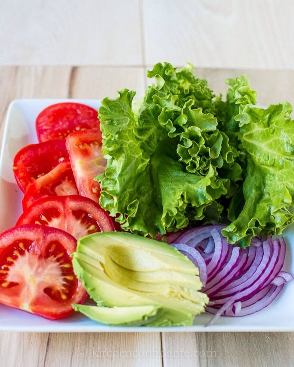 Clean all the vegetables like the tomato, lettuce, onion, and avocado with water.