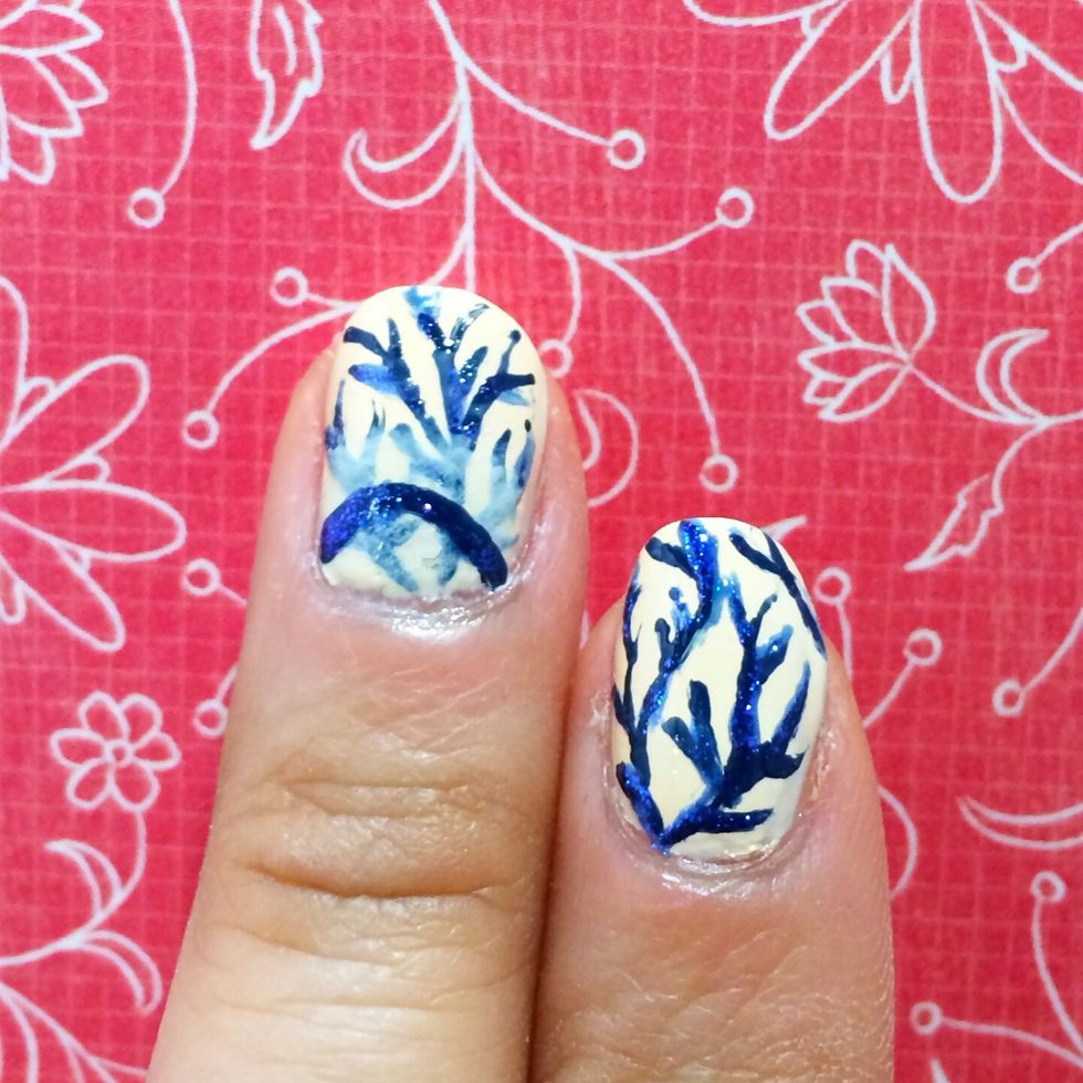 Clean off your nail art brush and dip it into a shimmery blue polish. Trace along some of the branches to create glistening highlights.