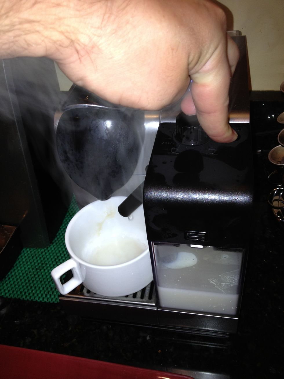 Clean the spout by holding down the black button on the milk apparatus until the machine stops making steam. BE CAREFUL to not burn yourself; the approach shown above is a good way to get hurt.