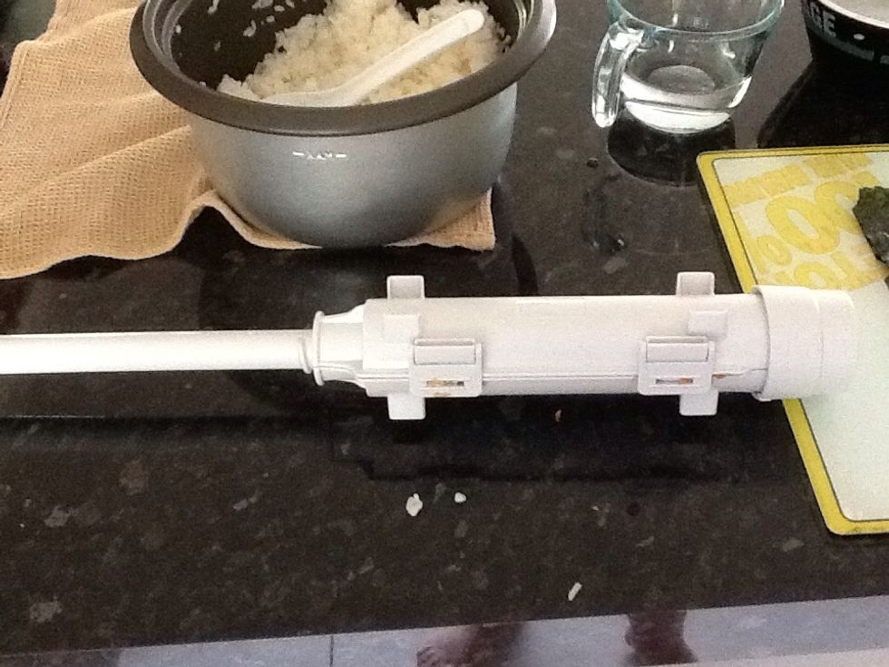 Close and shut the clasp things, and put the cap on the end. Now turn the plunger knob thing until it doesn't twist any more, this is about 5 turns. By doing this the sushi is being compressed.