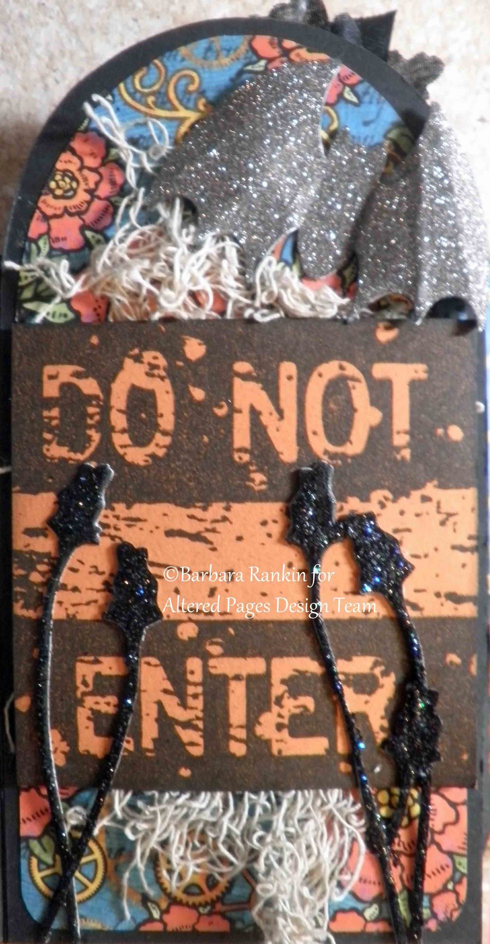 Close up of Page 1, Sin City Stamps Do Not Enter sign, die cut roses glittered with Stickles glitter glue, adhered over creepy cloth, punched Bat.