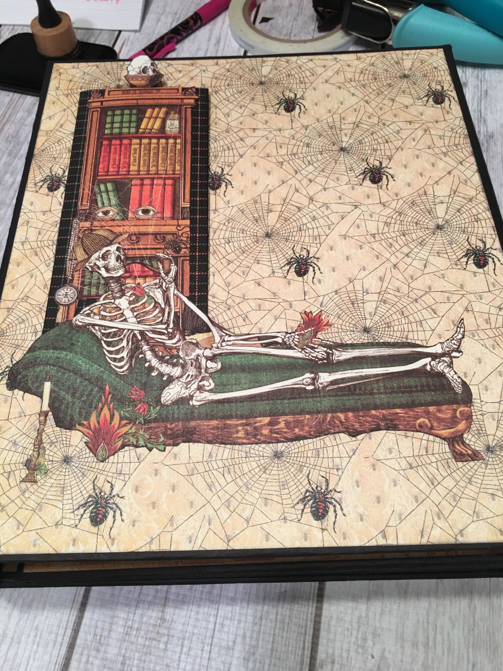 Clue down on to the left front side of the album cover.  Fussy cut out the skeleton on the fainting couch and glue to the front of the bookcase and on to the album cover.