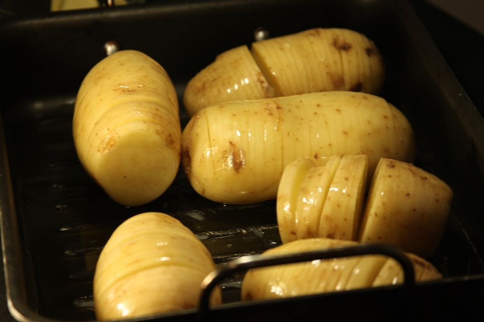 Coloque as batatas em uma assadeira. Jogue por cima um pouco de azeite com ervas e sal ao gosto.