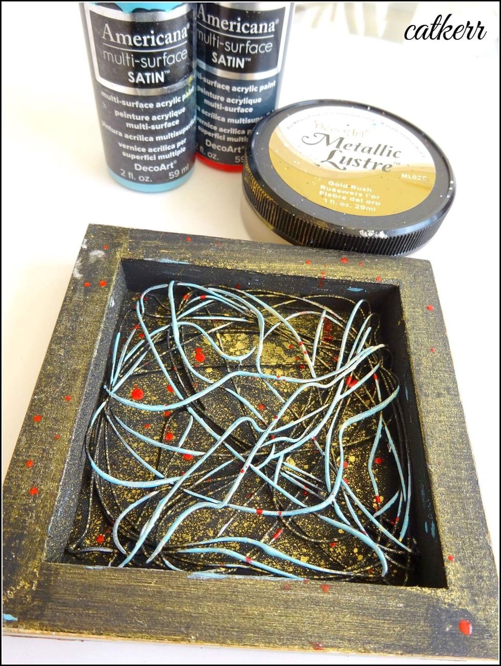 Color the wire in Teal paint. Splatter on some red. Add some Metallic Lustre to a small water bottle. Add water and mix thoroughly. Spray the shadowbox with liquid Metallic Lustre.