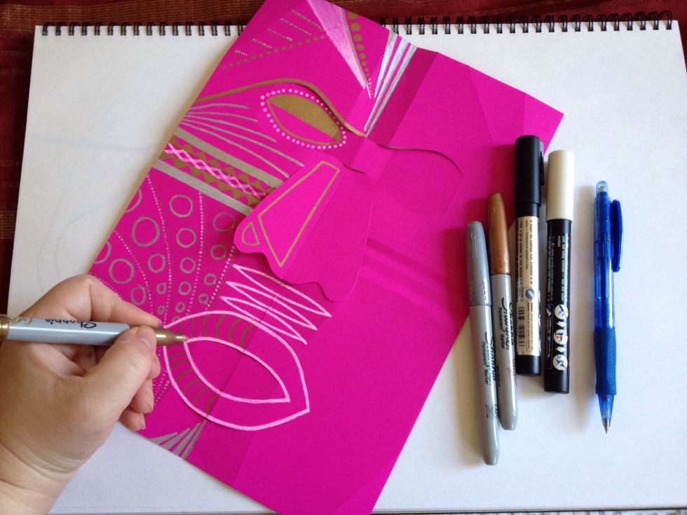 Colour your mask with paint or metallic markers. Symmetry is important in African masks so colour one half first.