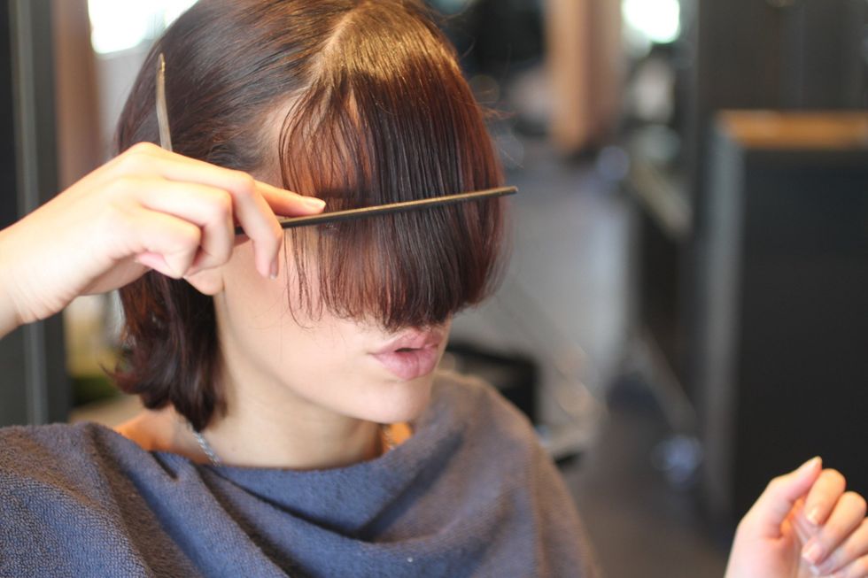 Comb your hair evenly across forehead. If your hair is thick, clip back the top half of your bangs so you can cut one layer at a time. If your hair is thin, you can cut it all at once.