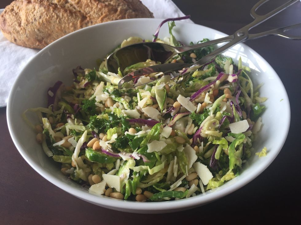 Combine bagged salad, pine nuts, parm cheese and dressing and let sit for 7-10 mintues