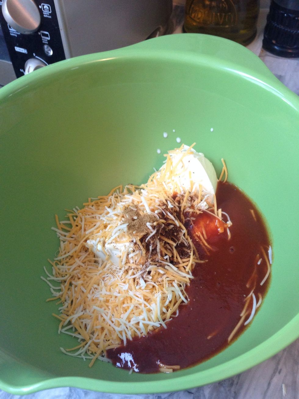 Combine Cream Cheese, Sour Cream, Half the Can of Enchilada Sauce, 1 Cup of Shredded Cheese, Cumin and Chili Powder.