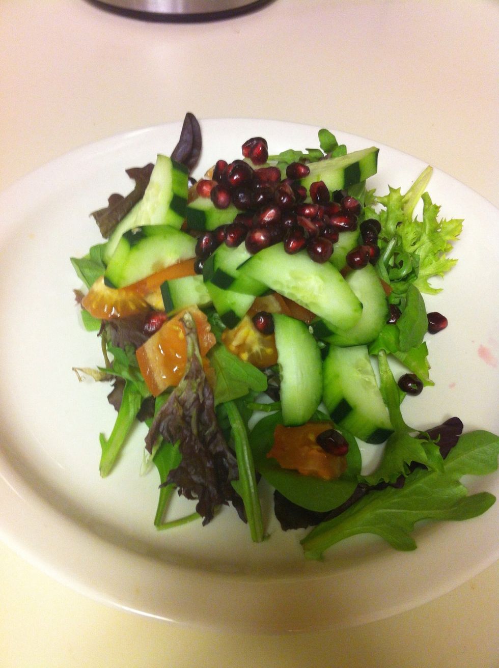 Combine mixed greens, cucumber, tomatoes and pomegranate seeds