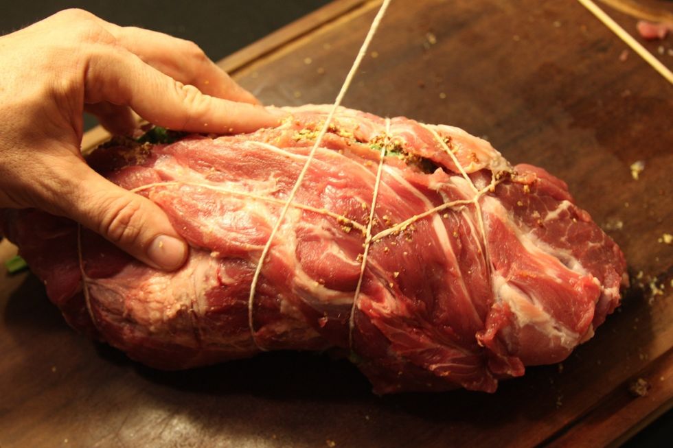 Come\u00e7e a enrolar o porco com o barbante at\u00e9 ficar completamente amarrado.