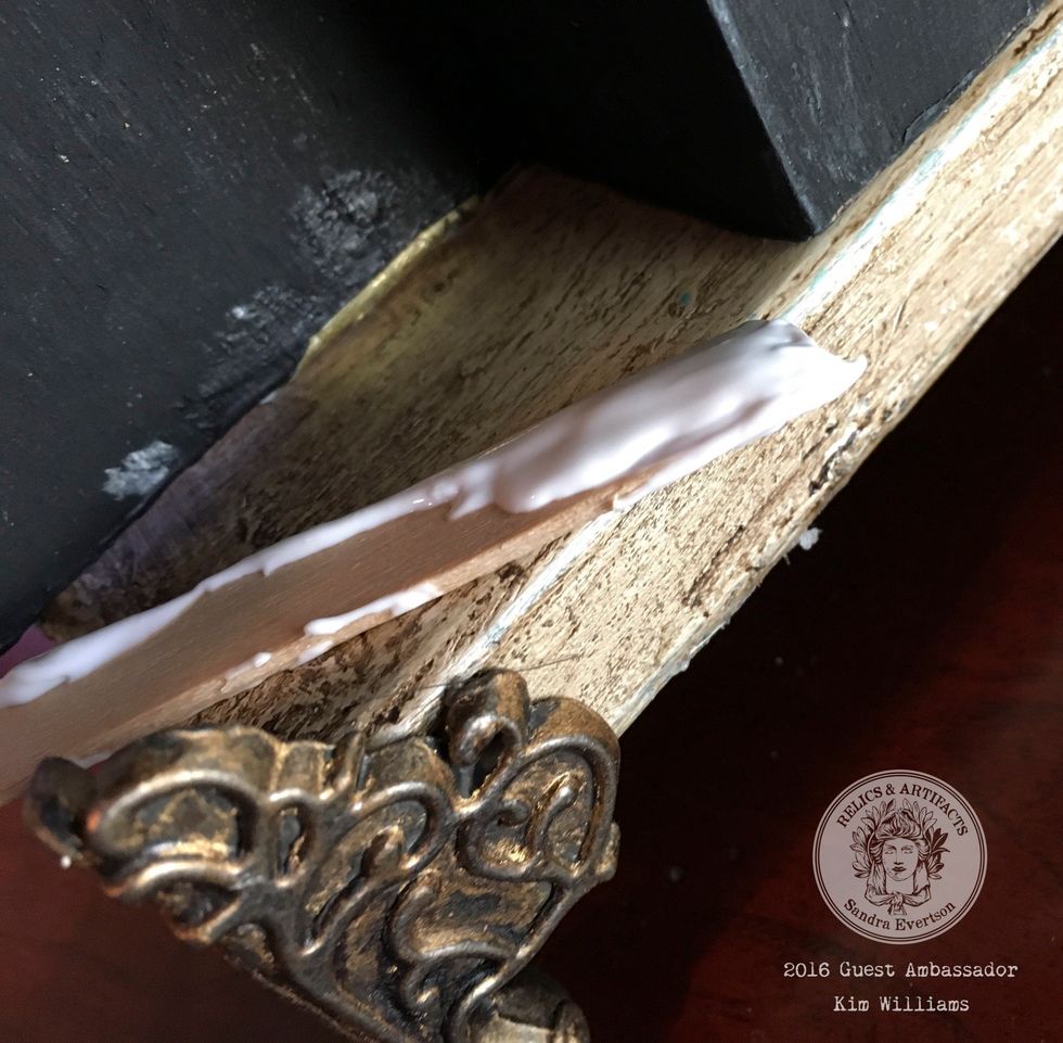 Complete the base cut enough metal trim to fit around the base. Use gold and buff and run the trim through your fingers. Glue trim and feet. And glue the framed box to the base