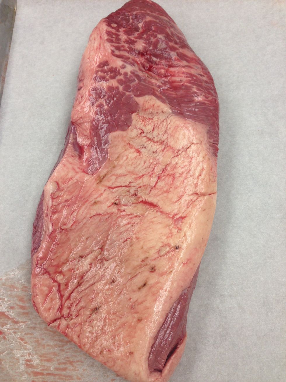 Completely defrost the brisket under refrigeration on lined sheet trays. This will take between 24 and 36 hours. Remove the trays from the walk-in and take them to your prep area.