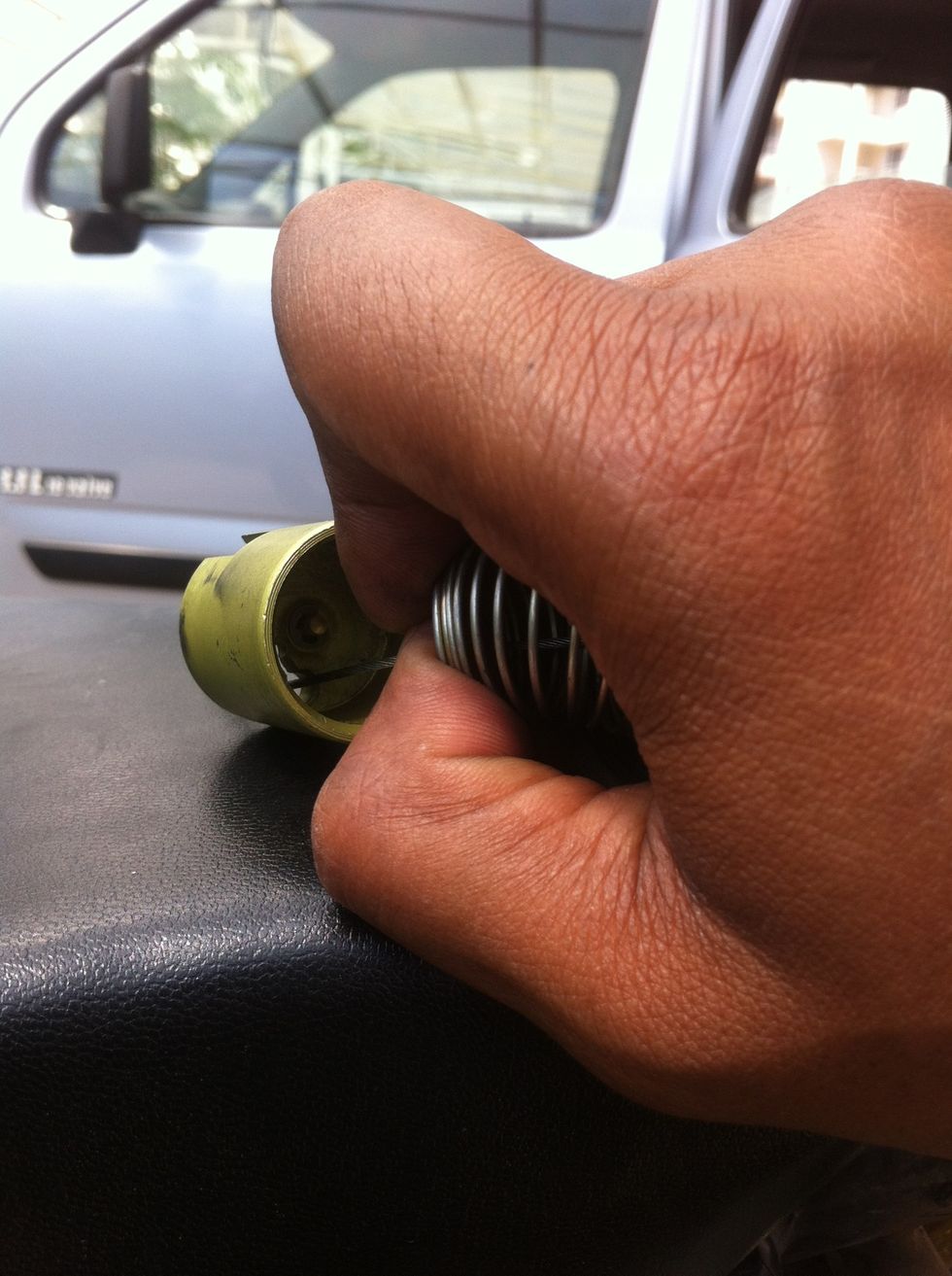 Compressing the spring will give more cable length to insert through the piston.