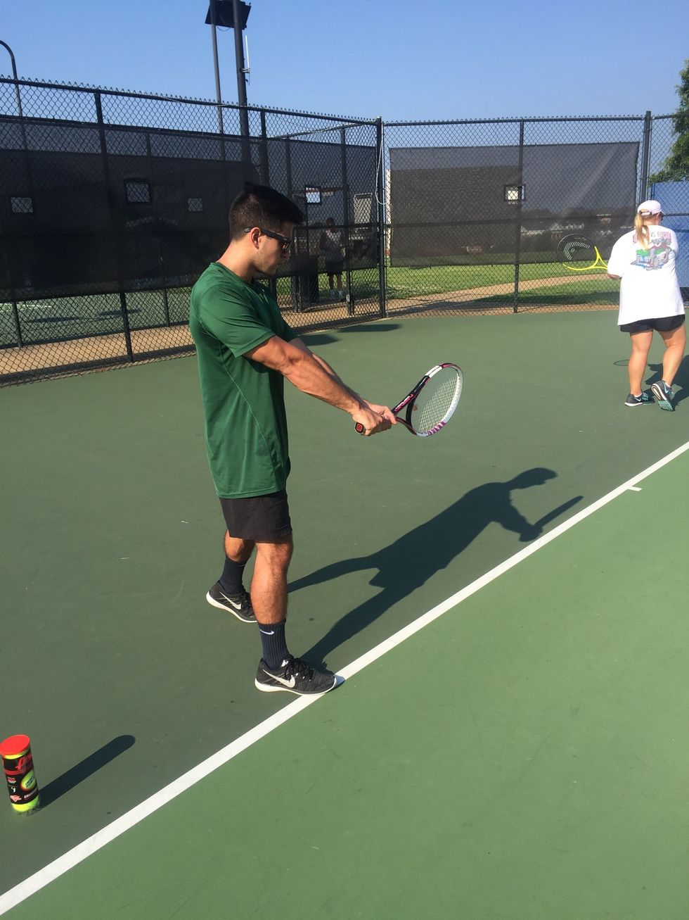 Contact: swing upward to meet the ball, bringing the racquet just forward to the lead foot. Transfer your weight from the back foot to the front.