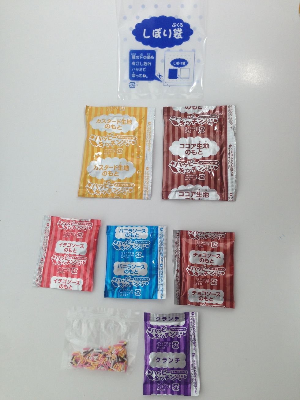 CONTENTS: From Top to Bottom-L to R~~CLEAR Pastry Bag-YELLOW Cake Mix-BROWN Cake Mix--RED Strawberry Frosting-BLUE Vanilla Frosting-BROWN Chocolate Frosting--SPRINKLES-PURPLE Crunchy Topping Mix