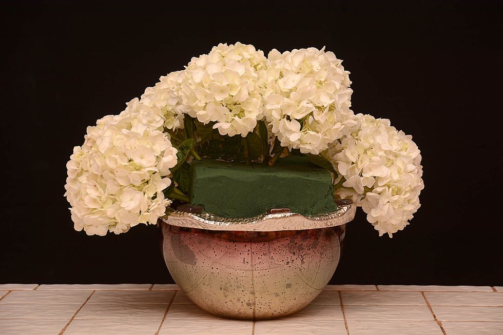 Continue adding hydrangea in a circular manner around the container as shown\u2026 (Easy isn't it? \u2026. At Rittners Floral School we make learning floral art quick and easy!)